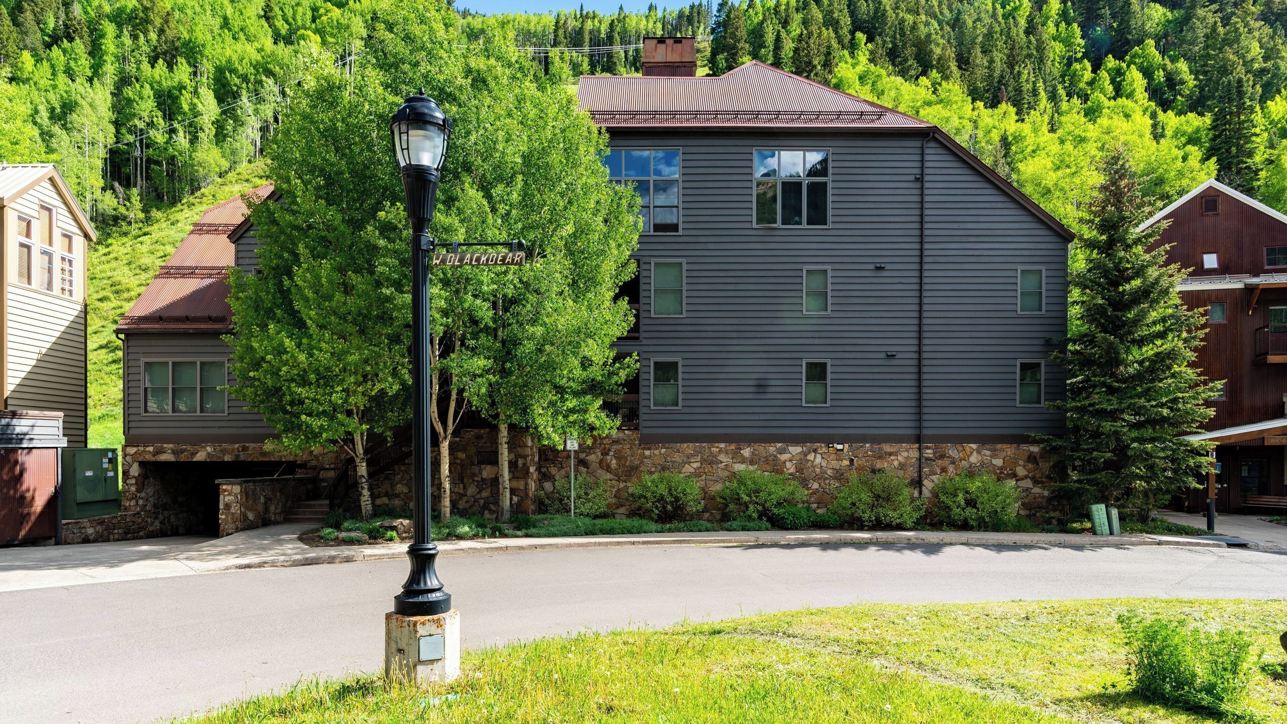 A residential building with a stone foundation, a metal roof, and a street lamp in front.