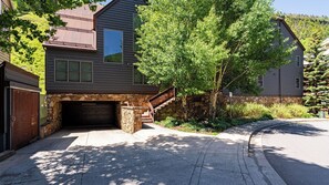 A two-story house with a stone foundation, a garage, and a staircase leading to the second floor.