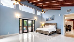 Un'ampia camera da letto con un letto grande, un ventilatore a soffitto e vista su un patio.