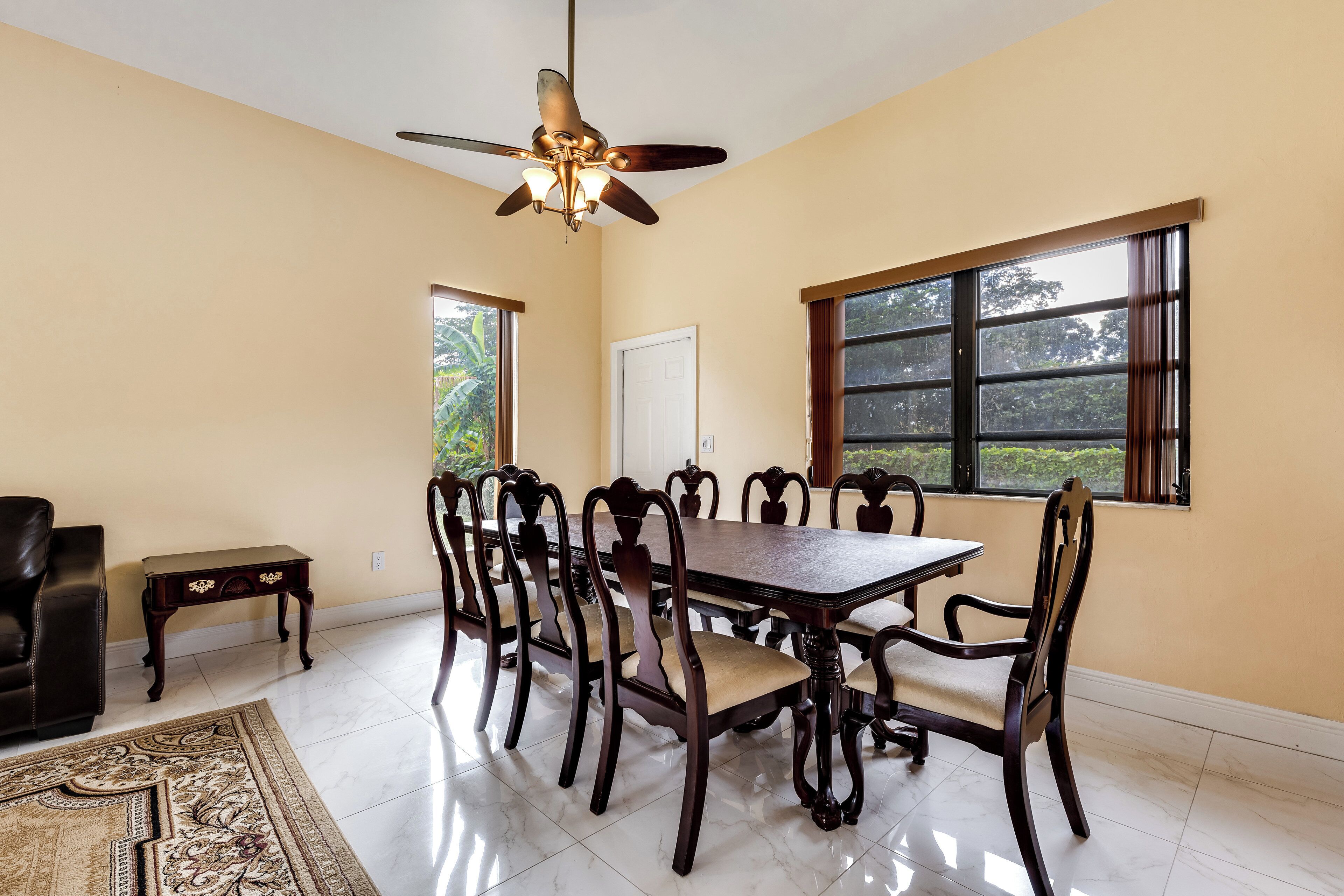 Un espace repas avec une grande table en bois, des chaises assorties et un ventilateur de plafond.
