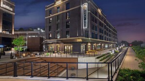 A modern hotel with a prominent entrance, outdoor seating area, and a well-lit facade. - Hotel Nickel Plate Fishers, Tapestry Collection By Hilton (Fishers)