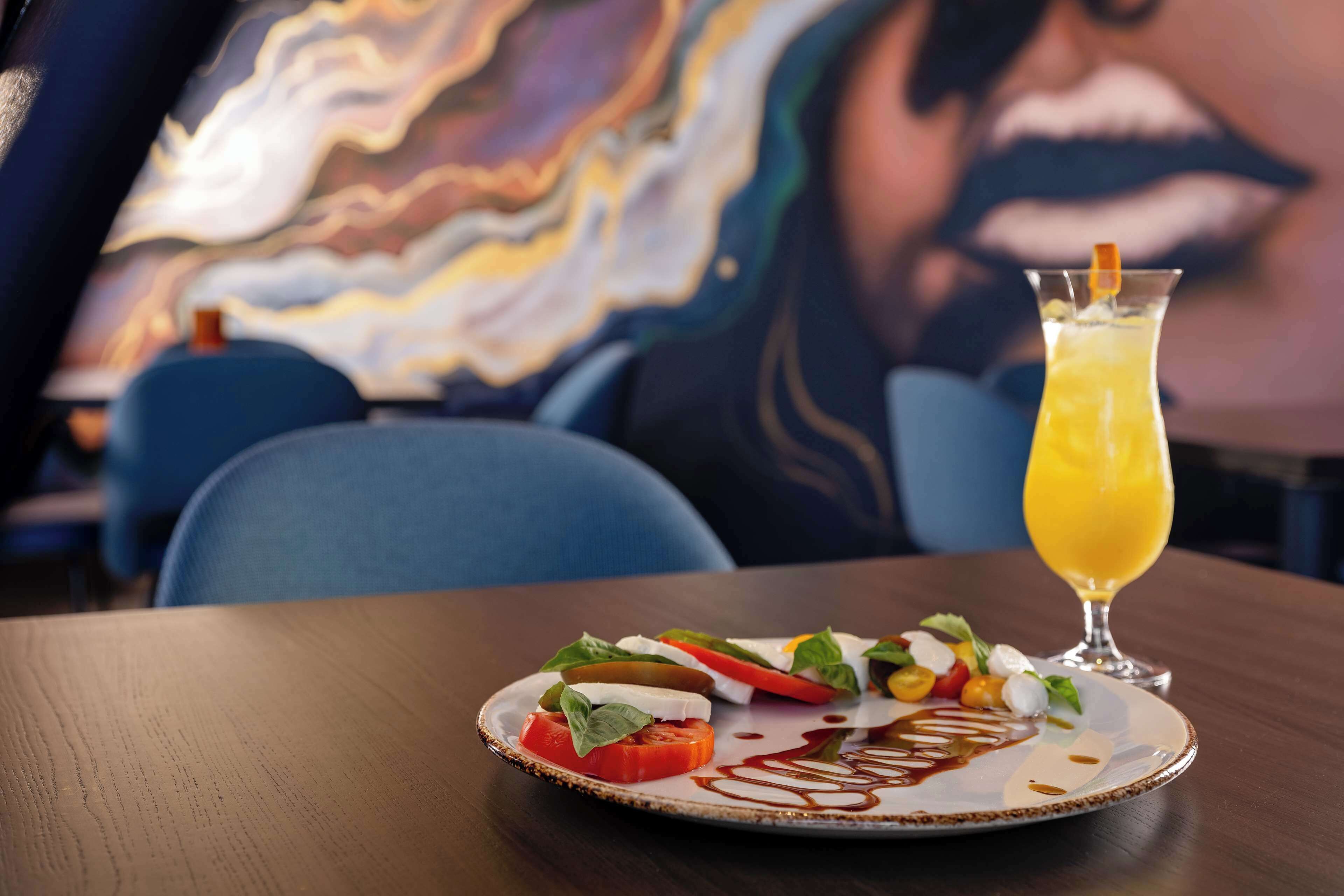 A plate of food with a glass of orange juice on a table.