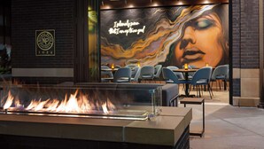 A restaurant with a fire feature, outdoor seating, and a mural on the wall. - Hotel Nickel Plate Fishers, Tapestry Collection By Hilton (Fishers)