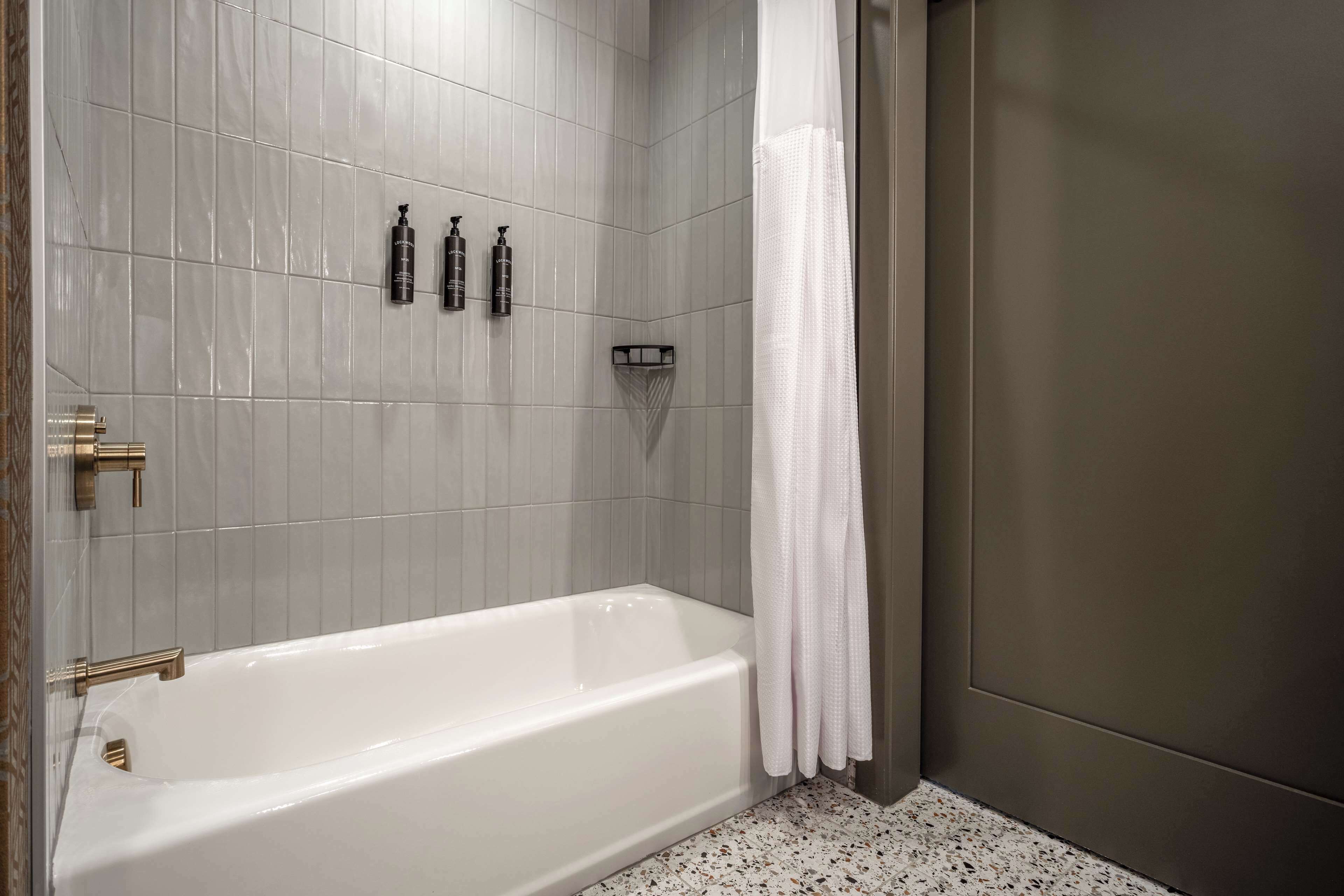 Un baño moderno con una bañera blanca, paredes con azulejos grises y una zona de ducha.