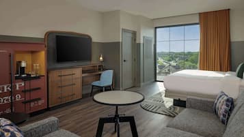 Une chambre d’hôtel avec un lit, un bureau avec une télévision, une chaise et une petite table.