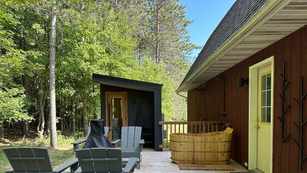 Una terraza de madera con mobiliario exterior y un jacuzzi.