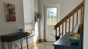 Una cocina moderna con piso de madera, un armario azul, una mesa negra y una ventana con persianas.