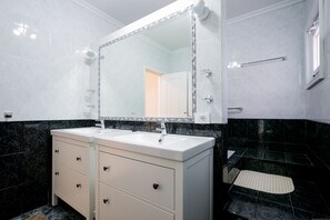 Bathroom features a dual sink vanity and a large mirror above it, with a towel rack and step stool nearby.