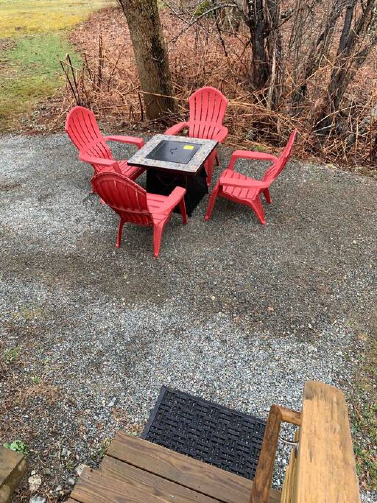 Un patio de grava con una mesa de madera y cuatro sillas rojas.