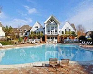 A swimming pool with lounge chairs and a building with a gabled roof in the background. - King's Creek Resort by Spinnaker  (Williamsburg)