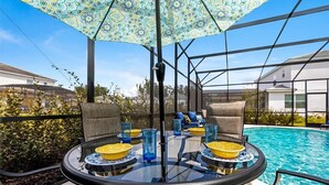 An outdoor patio with a glass table, chairs, and a pool. - 588 - Great Family Home near Disney, private pool - Bellavida Resort (Kissimmee)