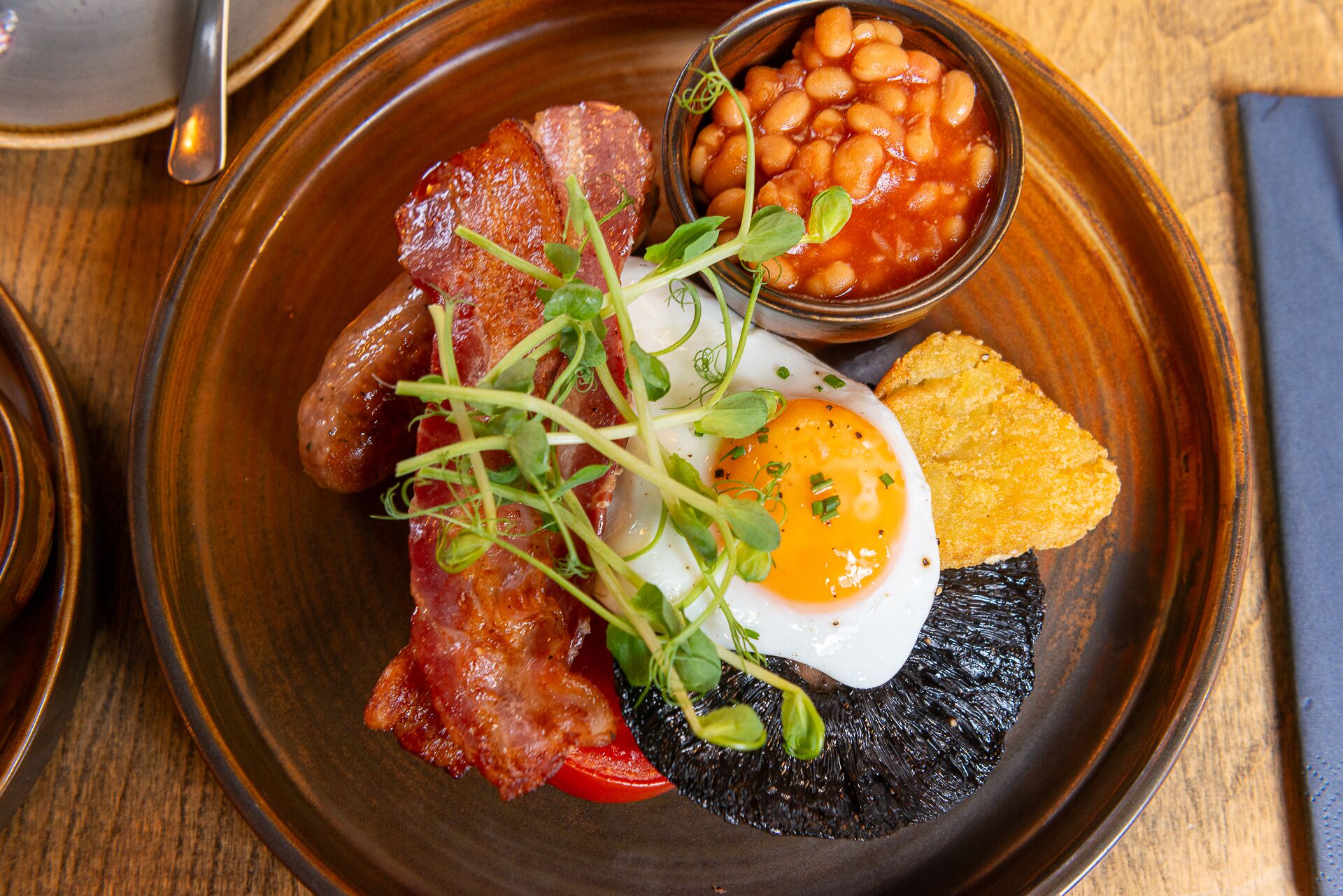 A breakfast plate with bacon, eggs, beans, and toast.