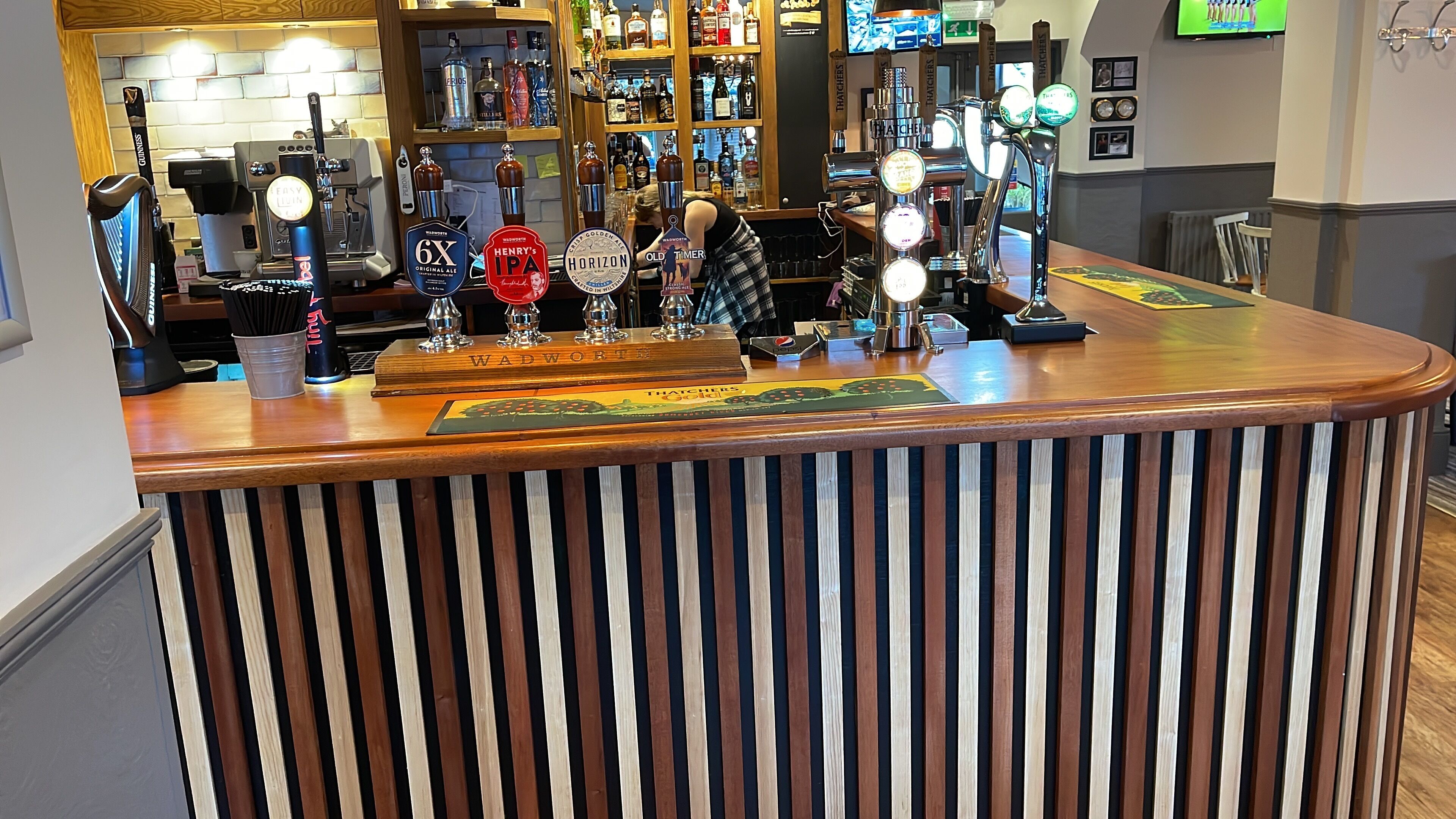 A bar area with multiple beer taps, a coffee machine, and a variety of liquor bottles.