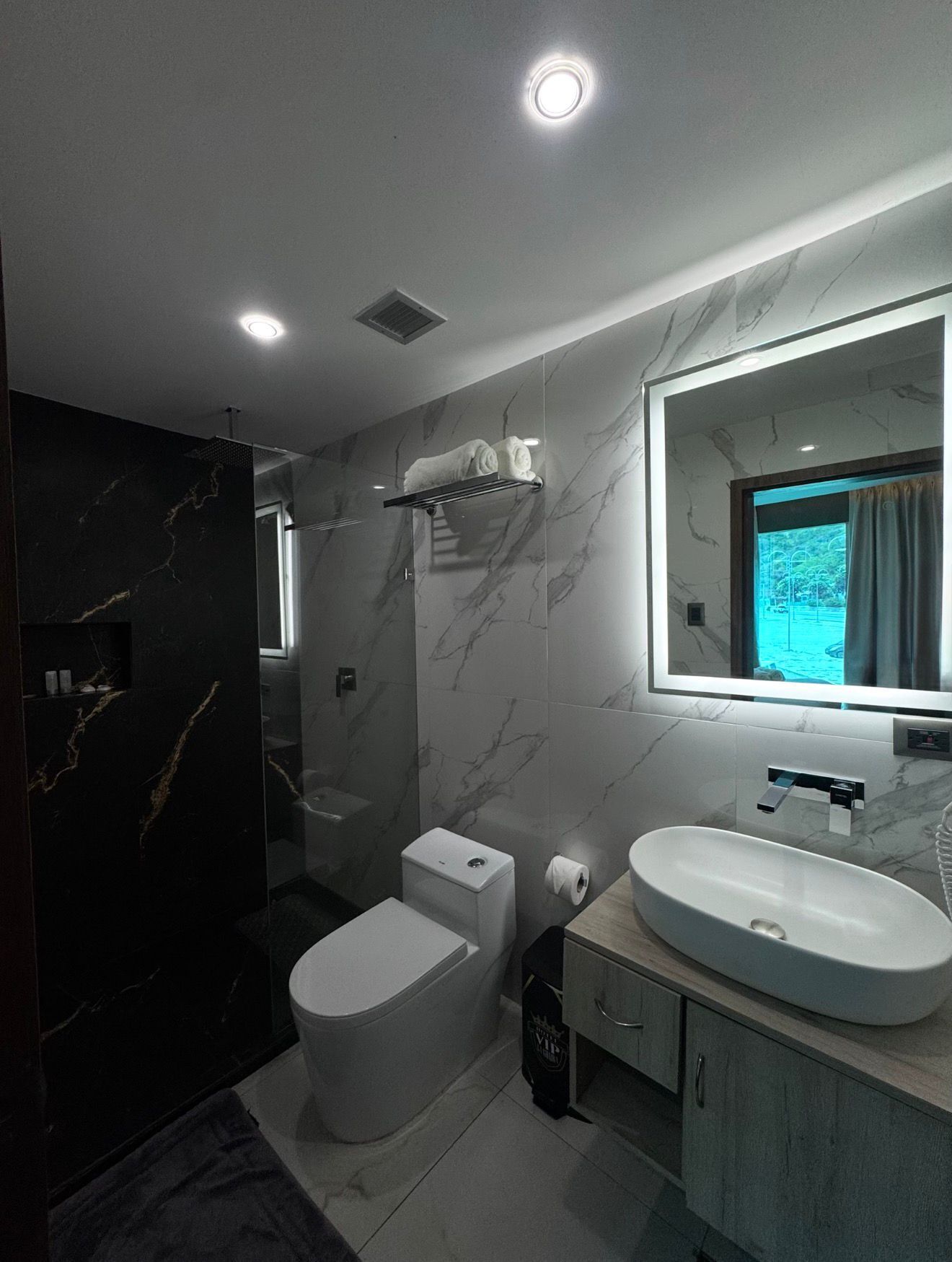 A modern bathroom with a toilet, sink, and mirror.