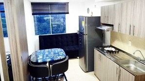 A compact kitchen with a refrigerator, stove, sink, and a dining area with a table and chairs. - Oronegroapartahoteles Espectacular Apartaestudio Amoblado Armenia, Quindío (Quindío)