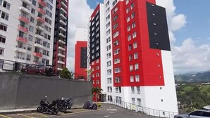 A parking area with motorcycles and a car, surrounded by high-rise buildings with balconies. - Oronegroapartahoteles Espectacular Apartaestudio Amoblado Armenia, Quindío (Quindío)