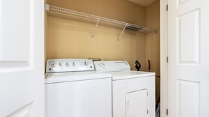 A laundry area with two white washing machines and a drying rack.
