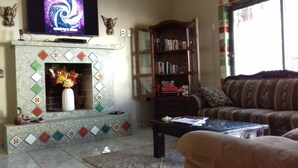 Una sala de estar con chimenea, una estantería, un sofá y una televisión.