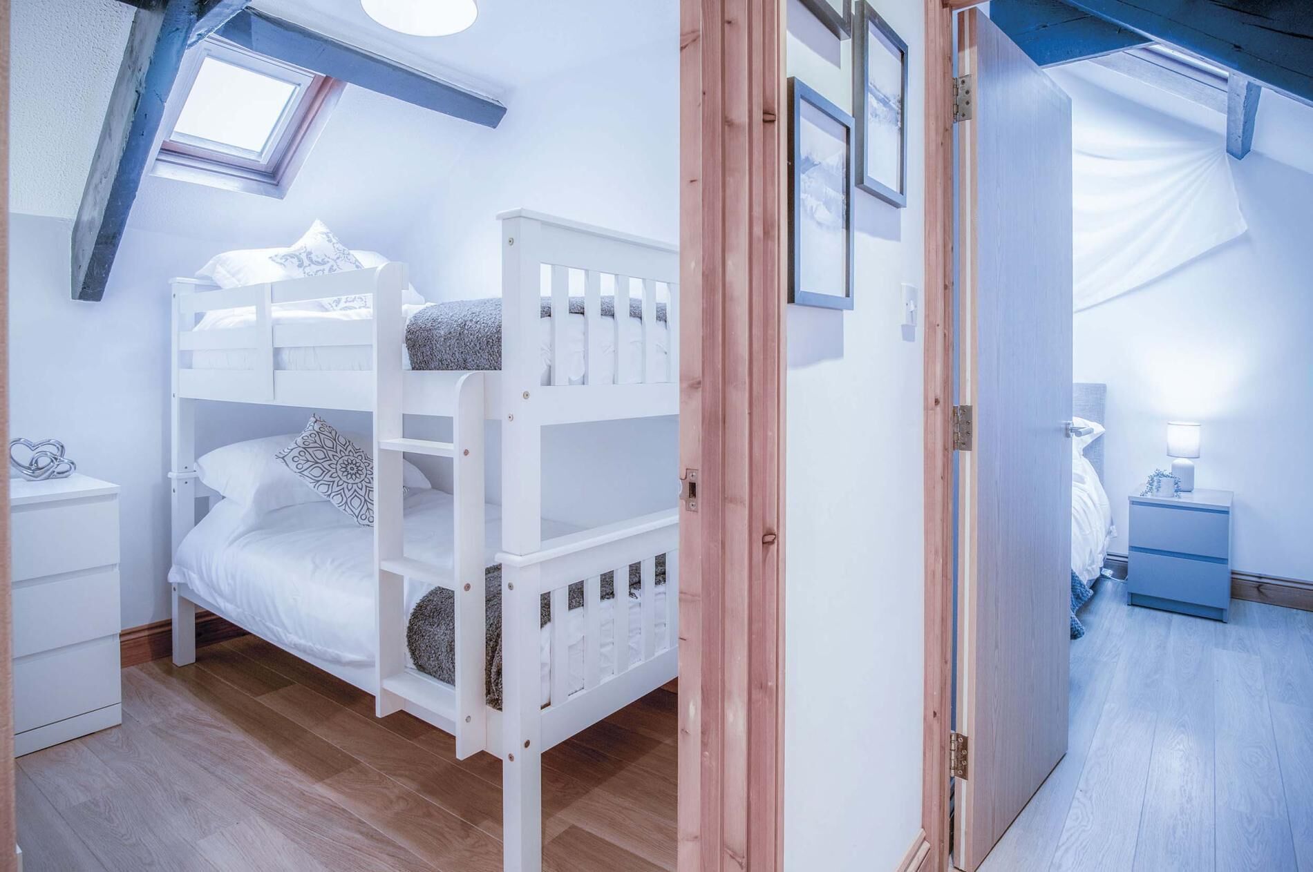 Une chambre avec un lit superposé, une lucarne, une table de chevet et une petite table d’appoint.
