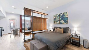 A modern bedroom with a large bed, a desk, and a small table.