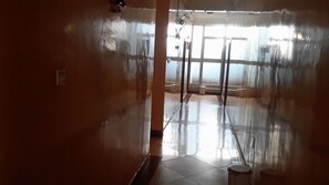 Un corridoio con pavimento lucido, una porta e una finestra con tende.