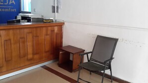 A reception desk with a sign, a computer, and a chair. - 70 Dereja Hotel (Addis Ababa)