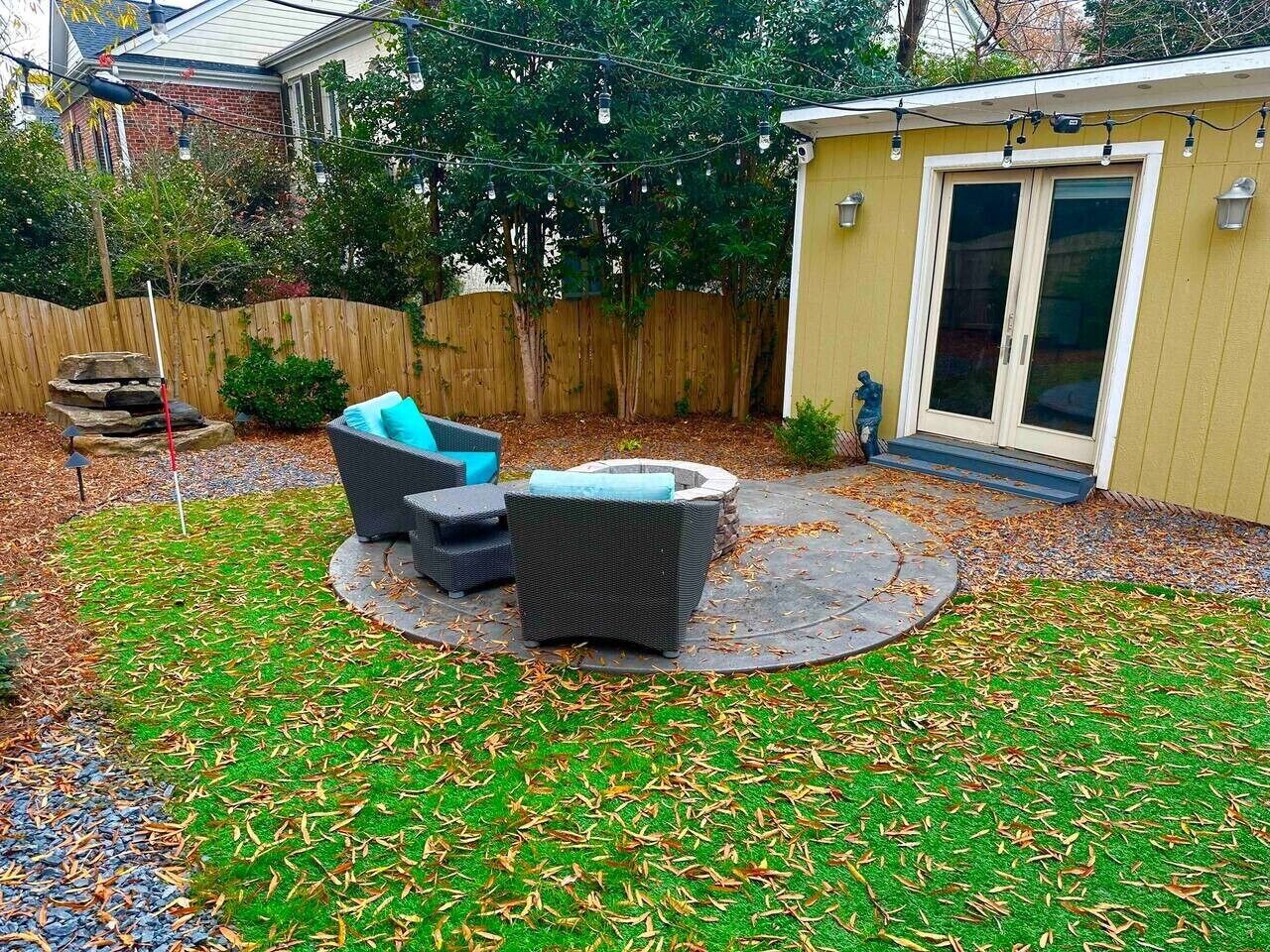 Un cortile con un patio circolare, mobili da esterno e un piccolo giardino.