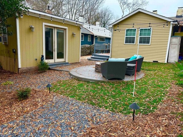 A backyard with a patio, outdoor furniture, and a small shed.
