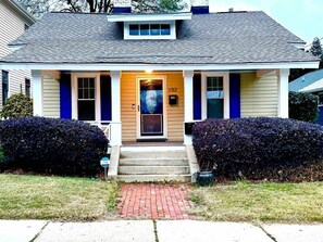 A two-story house with a front porch, a mailbox, and a number '932' on the door.