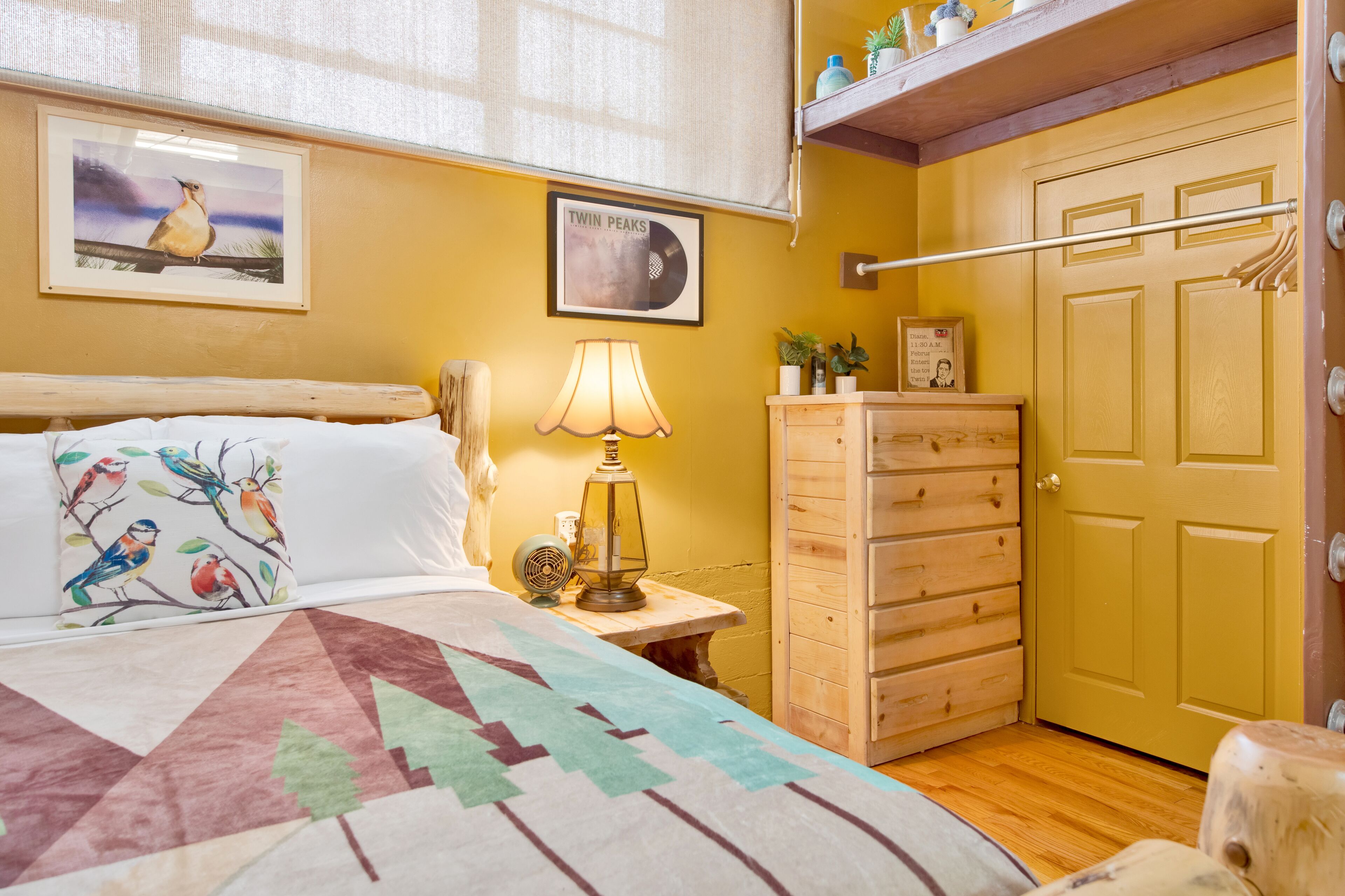 A bedroom with a bed, a nightstand, a lamp, a dresser, and a door.