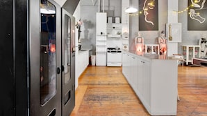 Une cuisine moderne avec des meubles blancs, un îlot central et des luminaires suspendus.