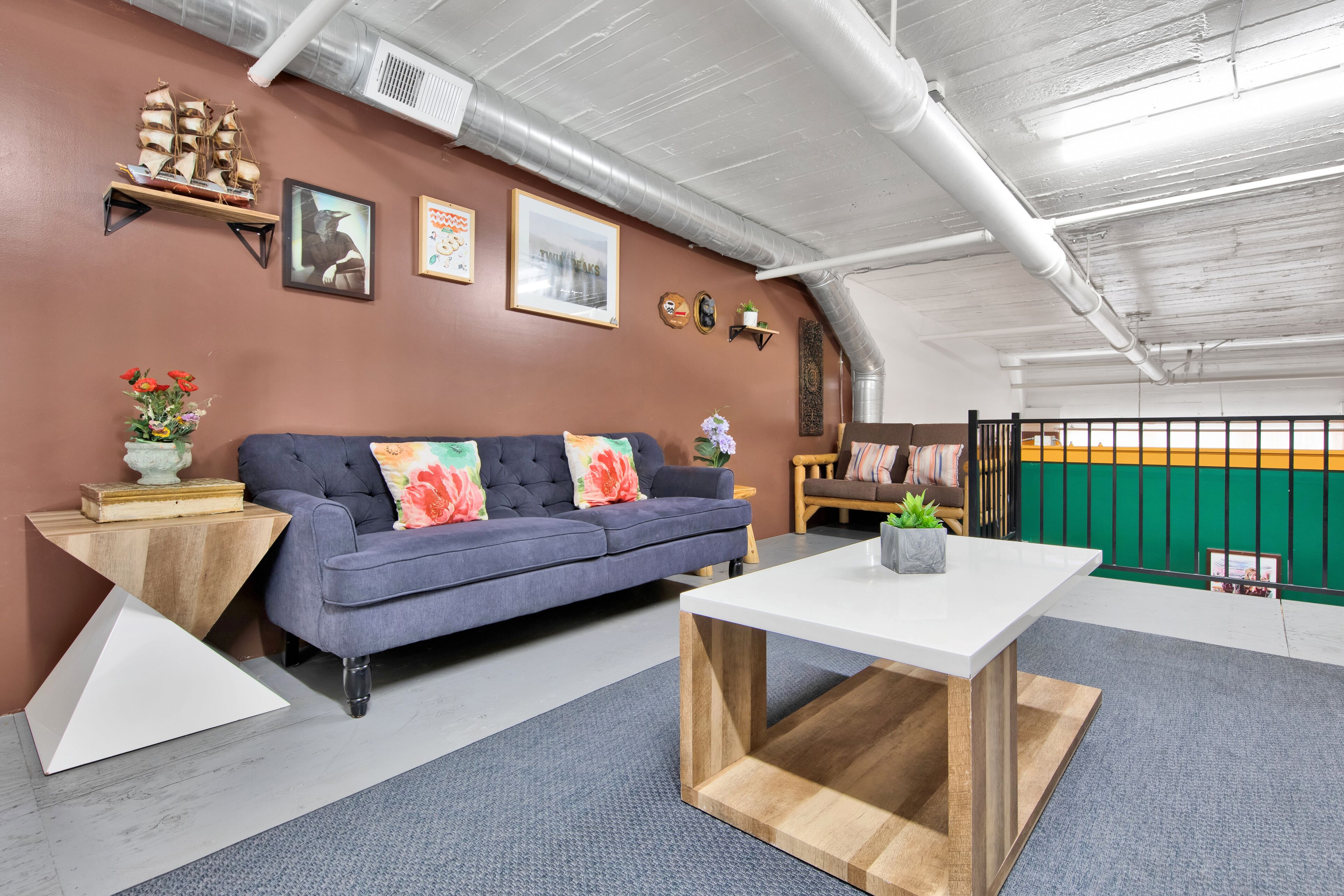 A modern living room with a blue sofa, a white coffee table, and decorative items on the walls.