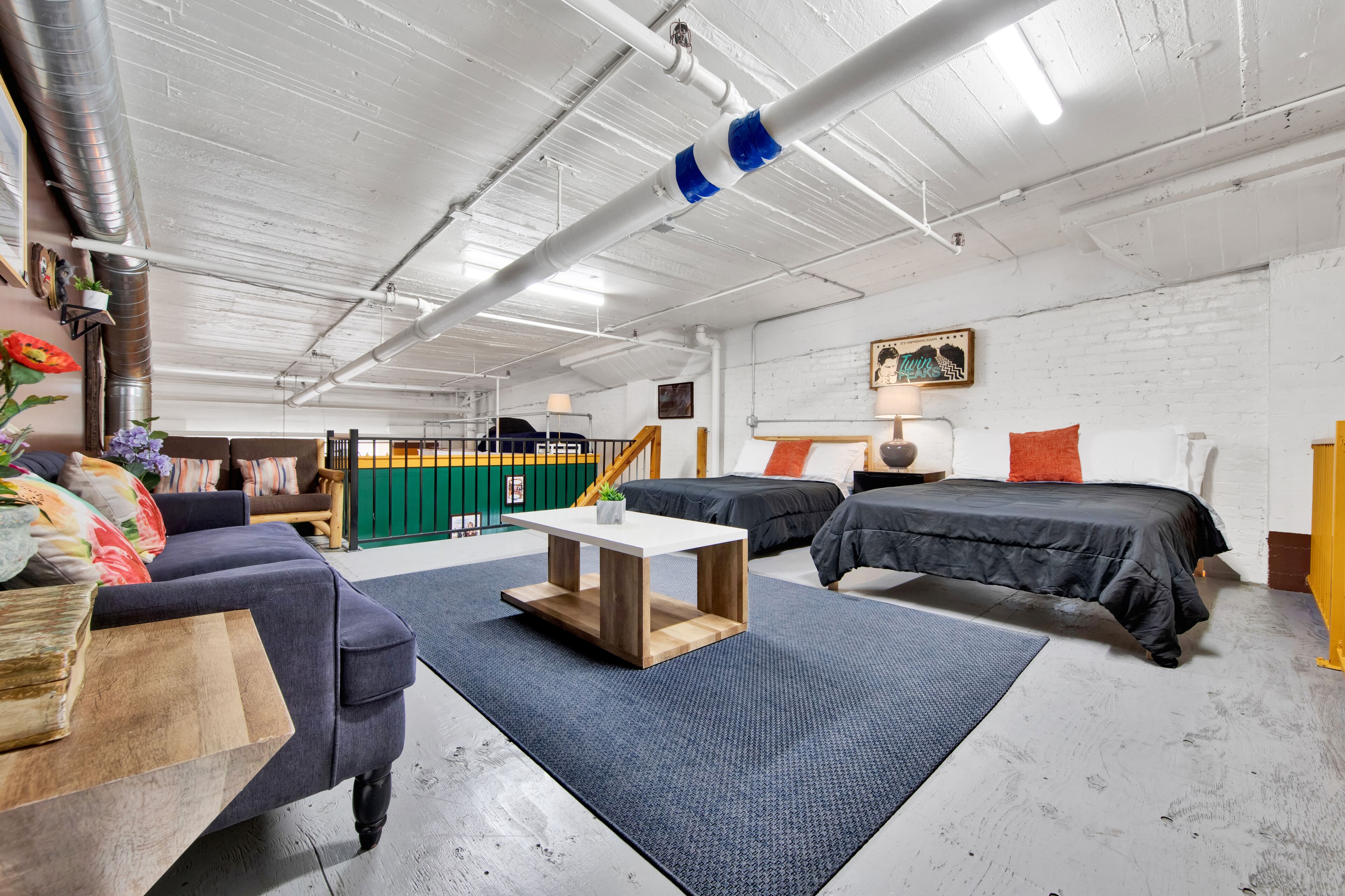 Una habitación moderna de estilo industrial con techos a la vista, un sofá, una cama y una mesita.