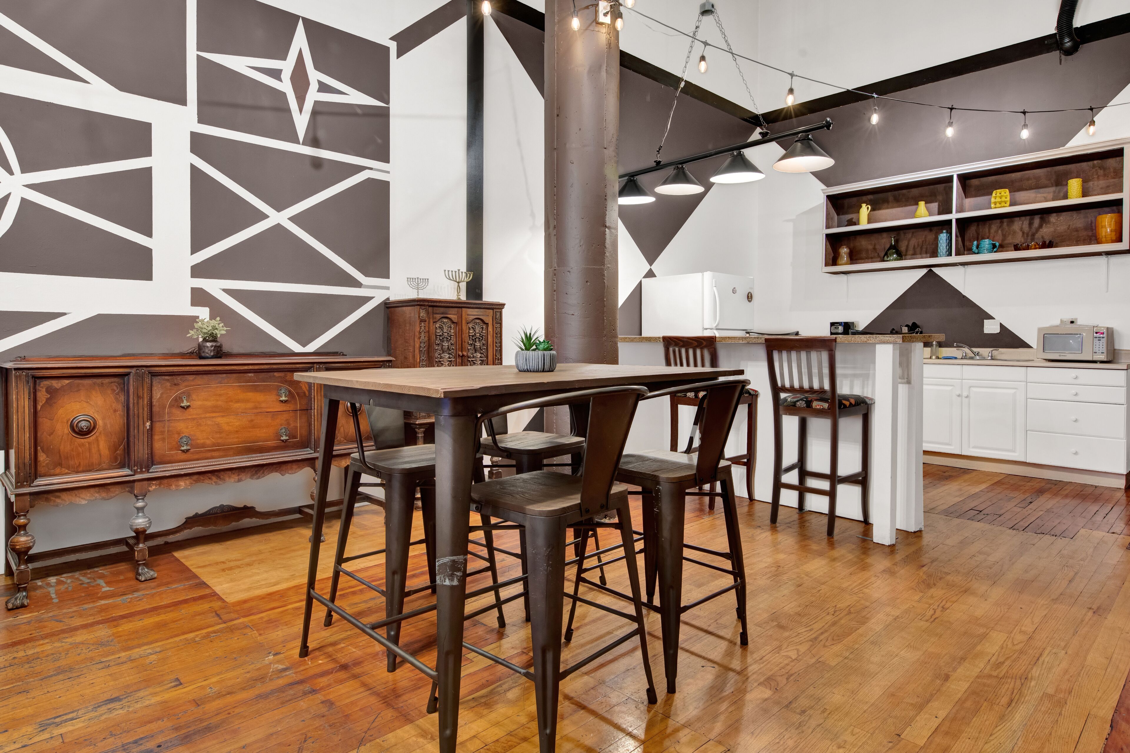 Une cuisine moderne avec une table à manger en bois, des tabourets de bar et un îlot central intégré.