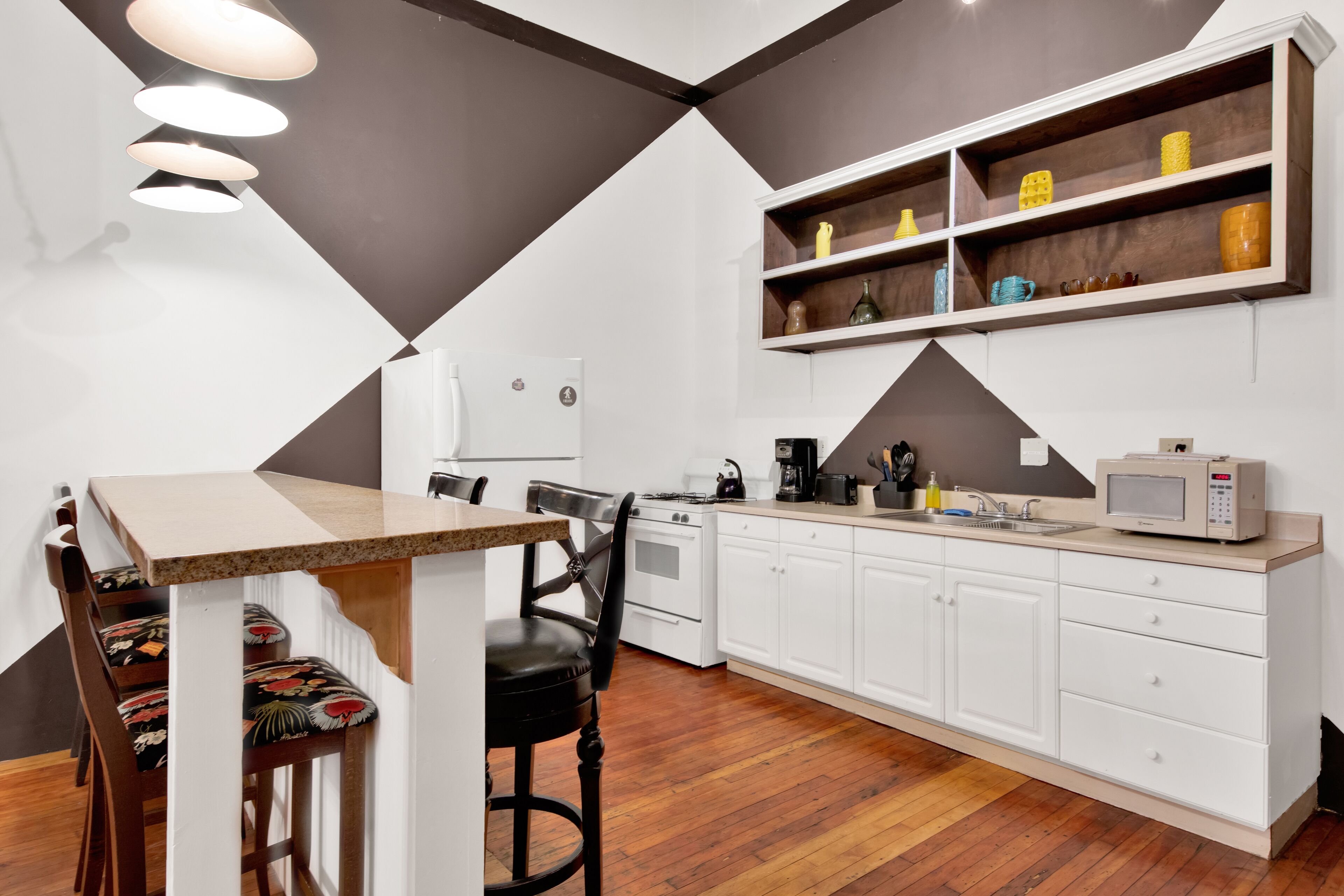 A modern kitchen with white cabinets, a wooden dining table, and a built-in microwave.