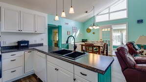 A kitchen with white cabinets, a double sink, and a dining area with a table and chairs. - Private Waterfront Retreat with Breathtaking Views. Pet-friendly! (Belhaven)