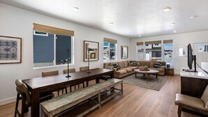 A spacious living room with a wooden dining table, a sofa, and a television.