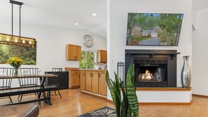 A modern living room with a fireplace, dining area, and kitchen. - Hot Tub - Game Garage. Peaceful 1 Level Lake Limerick Retreat with Fire-pit. (Shelton)