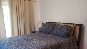 Ein Schlafzimmer mit Bett, Deckenventilator und Nachttisch mit Lampe.