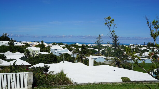 Ein Küstenwohngebiet mit weißen Häusern, blauem Himmel und Blick auf den Ozean.