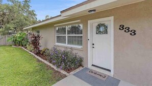 A single-story house with a beige exterior, a white door, and the number 333 on the wall. - The Peaceful Place (Sarasota)