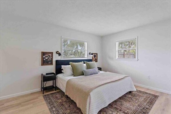 A bedroom with a bed, two bedside tables, a rug, and two windows. - The Peaceful Place (Sarasota)