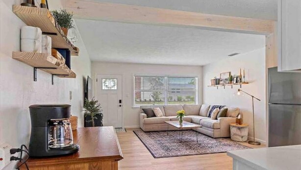 A modern kitchen with wooden shelves, a coffee maker, a sofa, and a dining area. - The Peaceful Place (Sarasota)