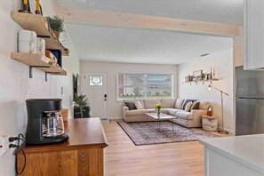 A modern kitchen with wooden shelves, a coffee maker, a sofa, and a dining area. - The Peaceful Place (Sarasota)