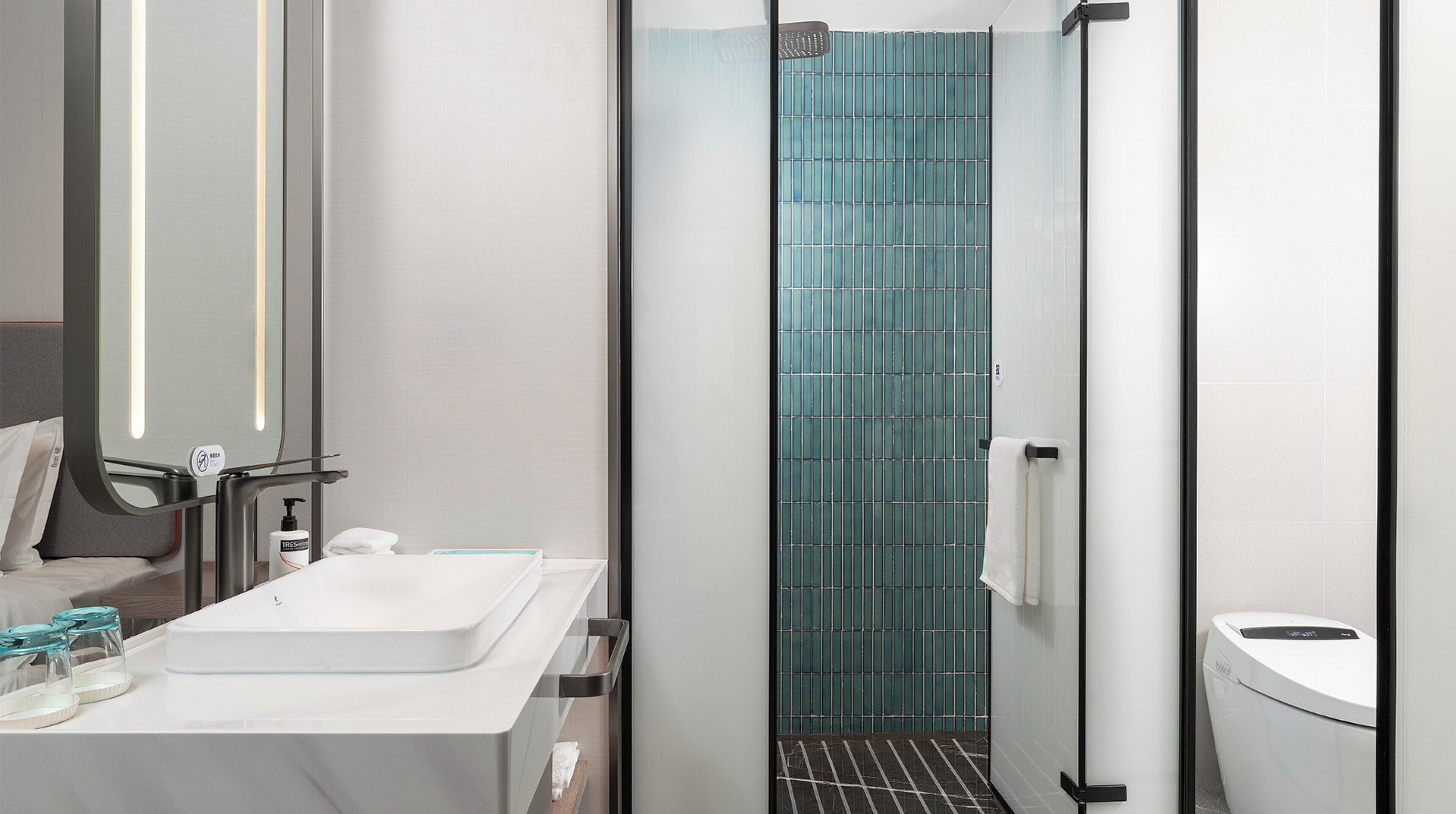 A modern bathroom with a white sink, a glass shower enclosure, and a toilet.