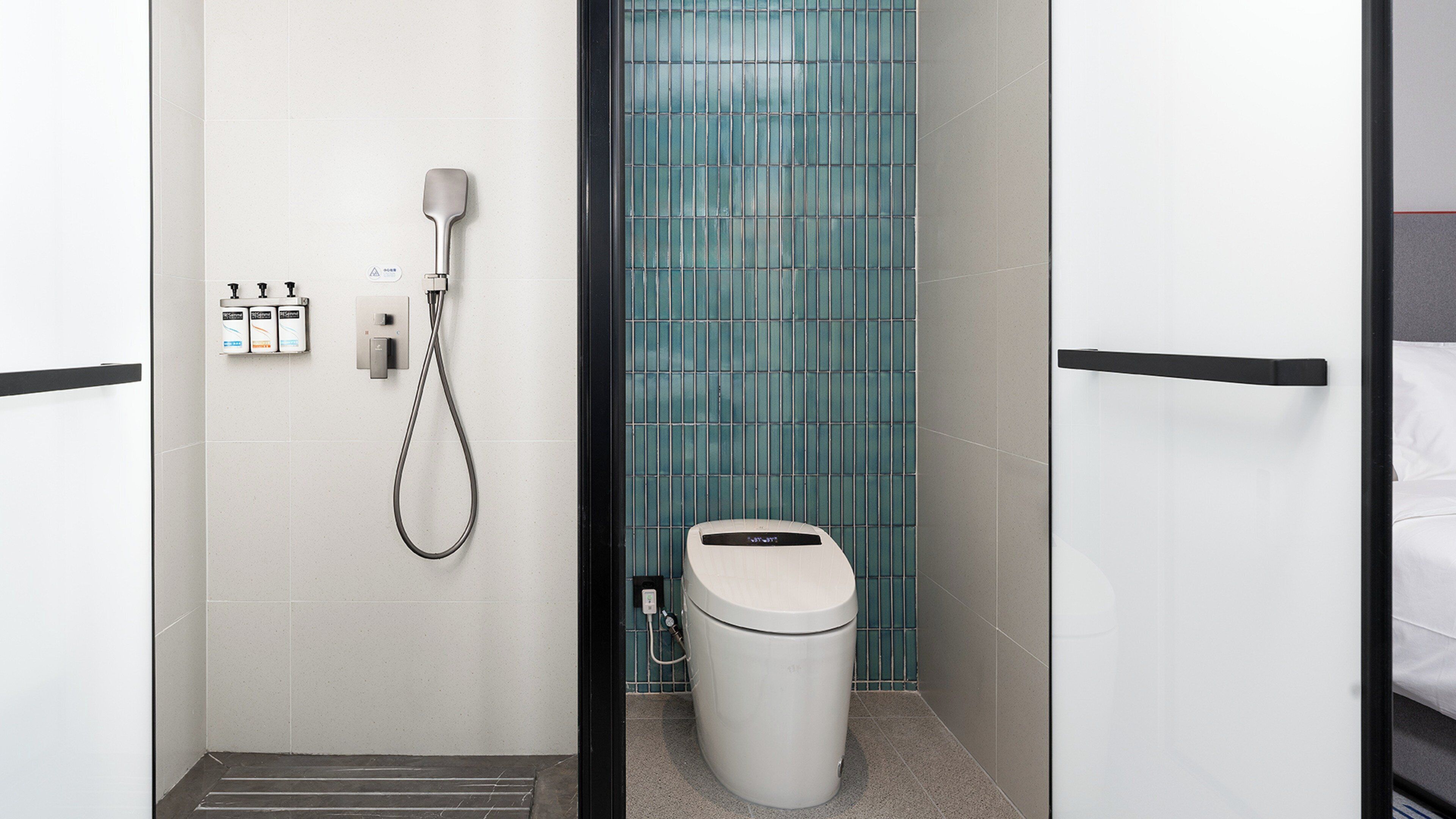 A modern bathroom with a shower, toilet, and a tiled wall.