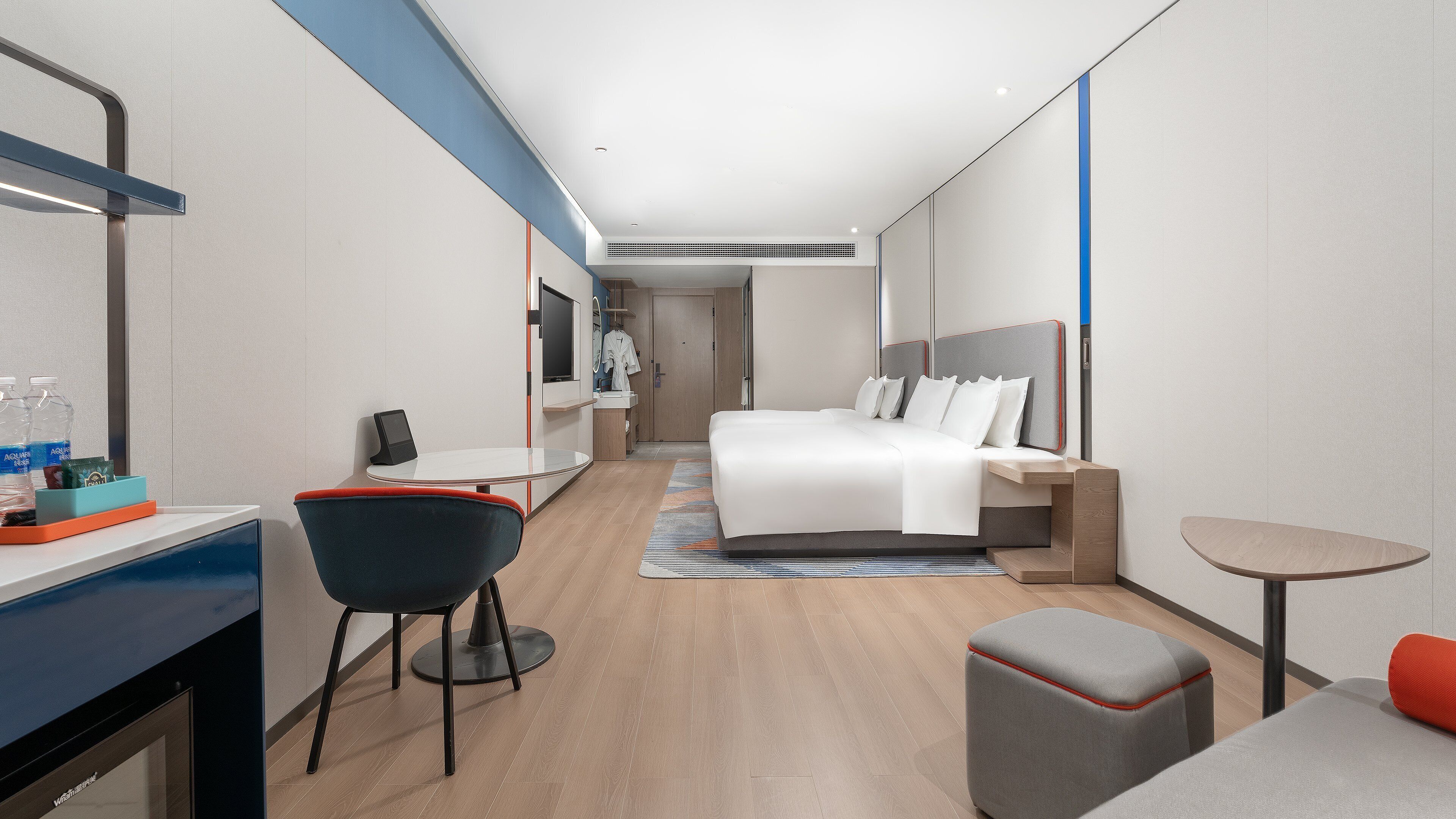 Une chambre d’hôtel moderne équipée d’un lit, d’une table de chevet, d’une chaise, d’un bureau et d’une petite table.