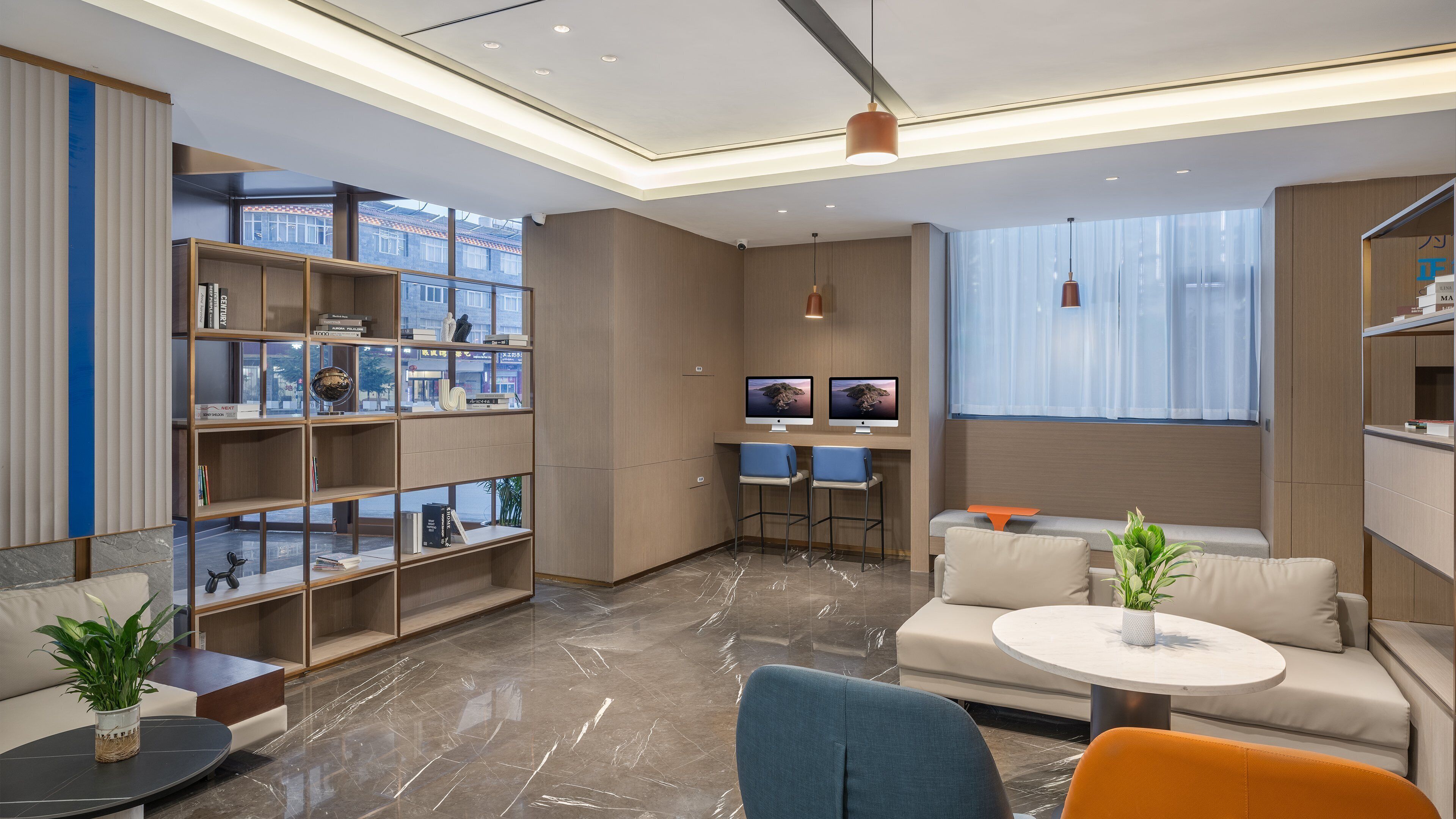 Uma sala de estar moderna com um sofá, dois bancos altos, uma mesa de centro redonda e uma estante de livros.