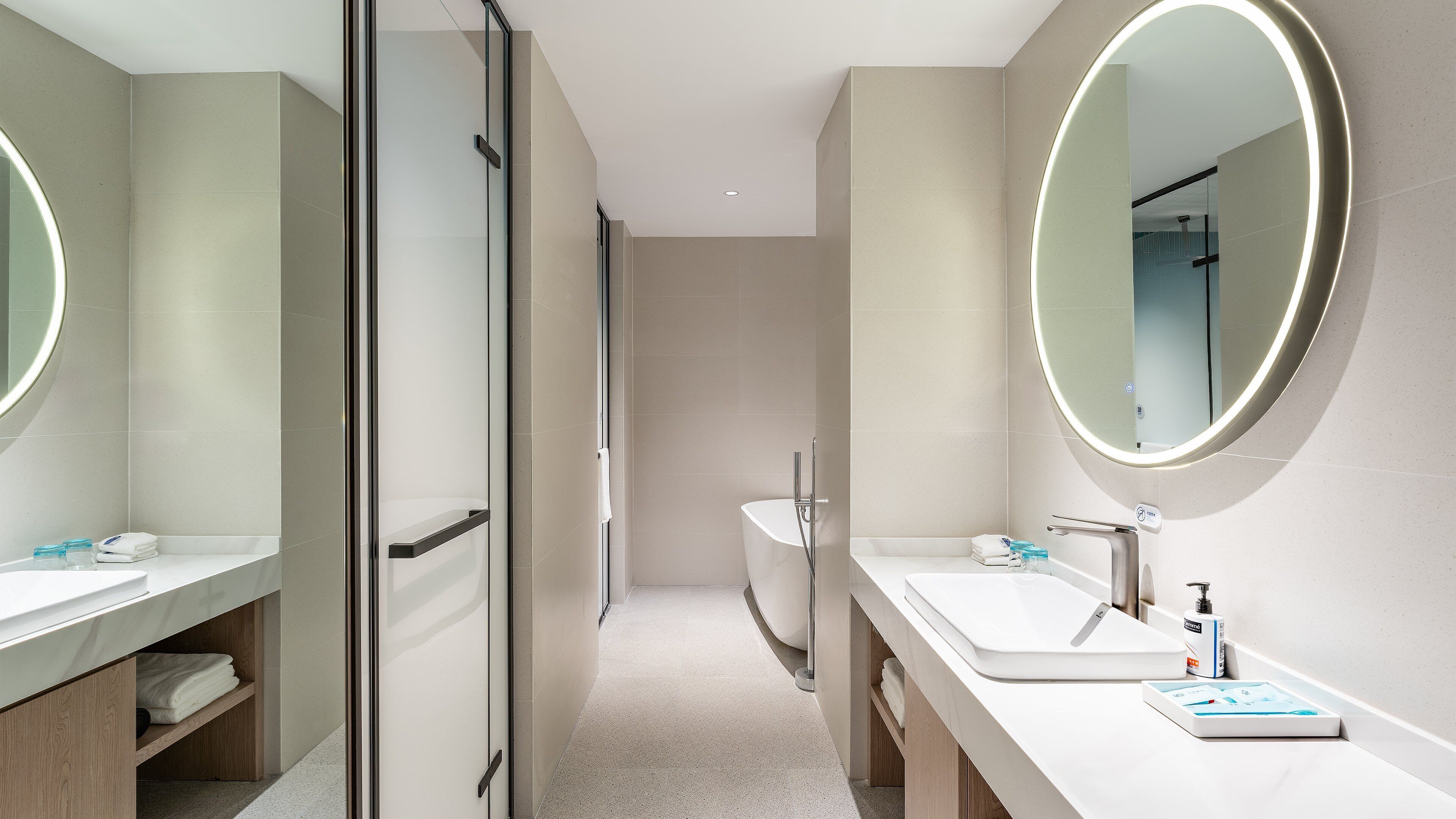 A modern bathroom with two sinks, a glass shower enclosure, and a large mirror.