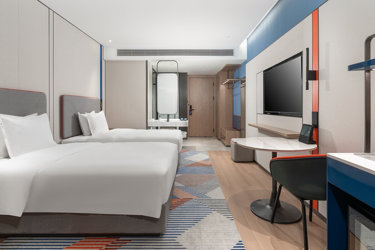 Een hotelkamer met een bed, een bureau, een televisie en een badkamer.